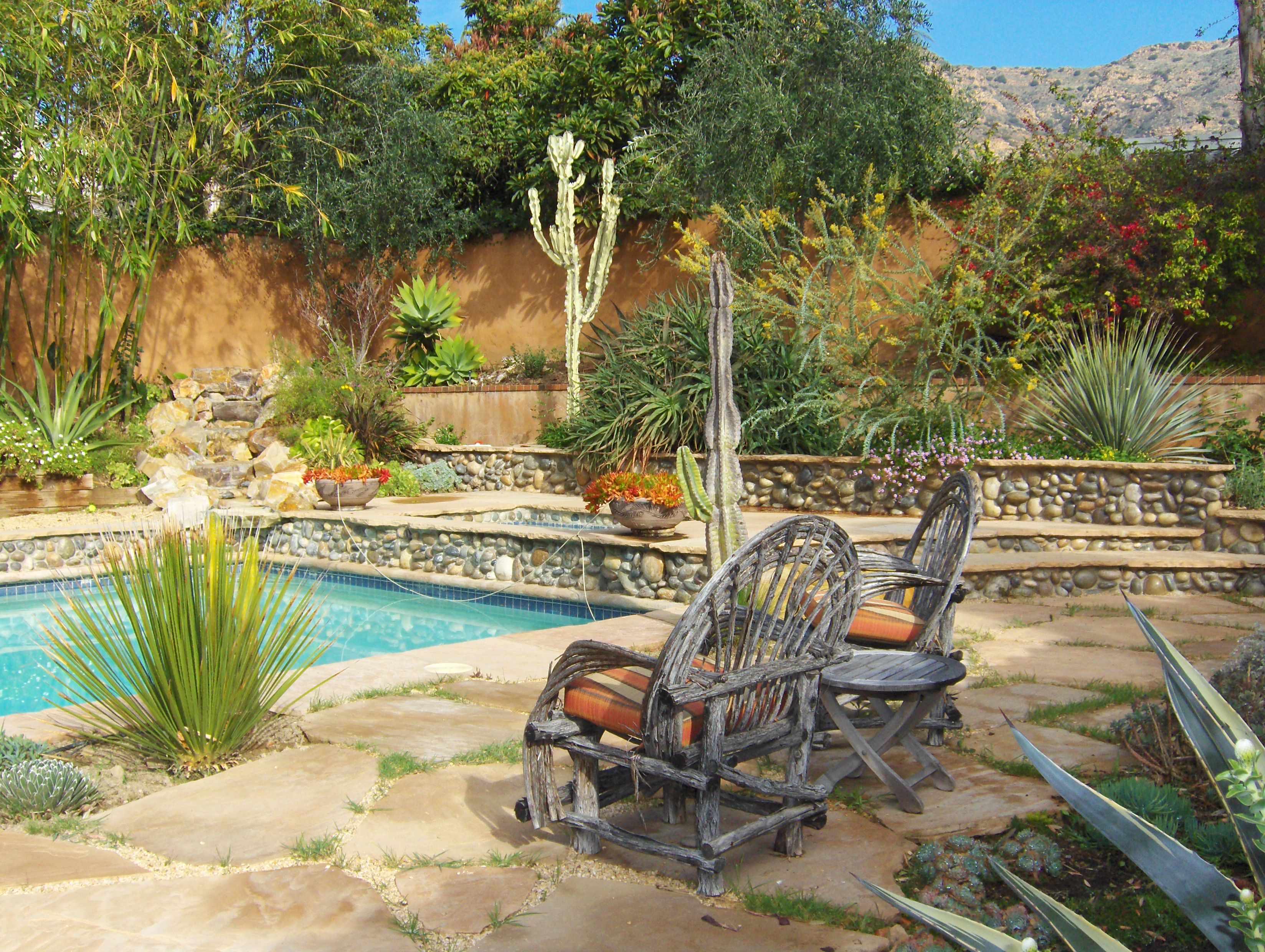 Deck chairs by pool in Mediterranean-style backyard.