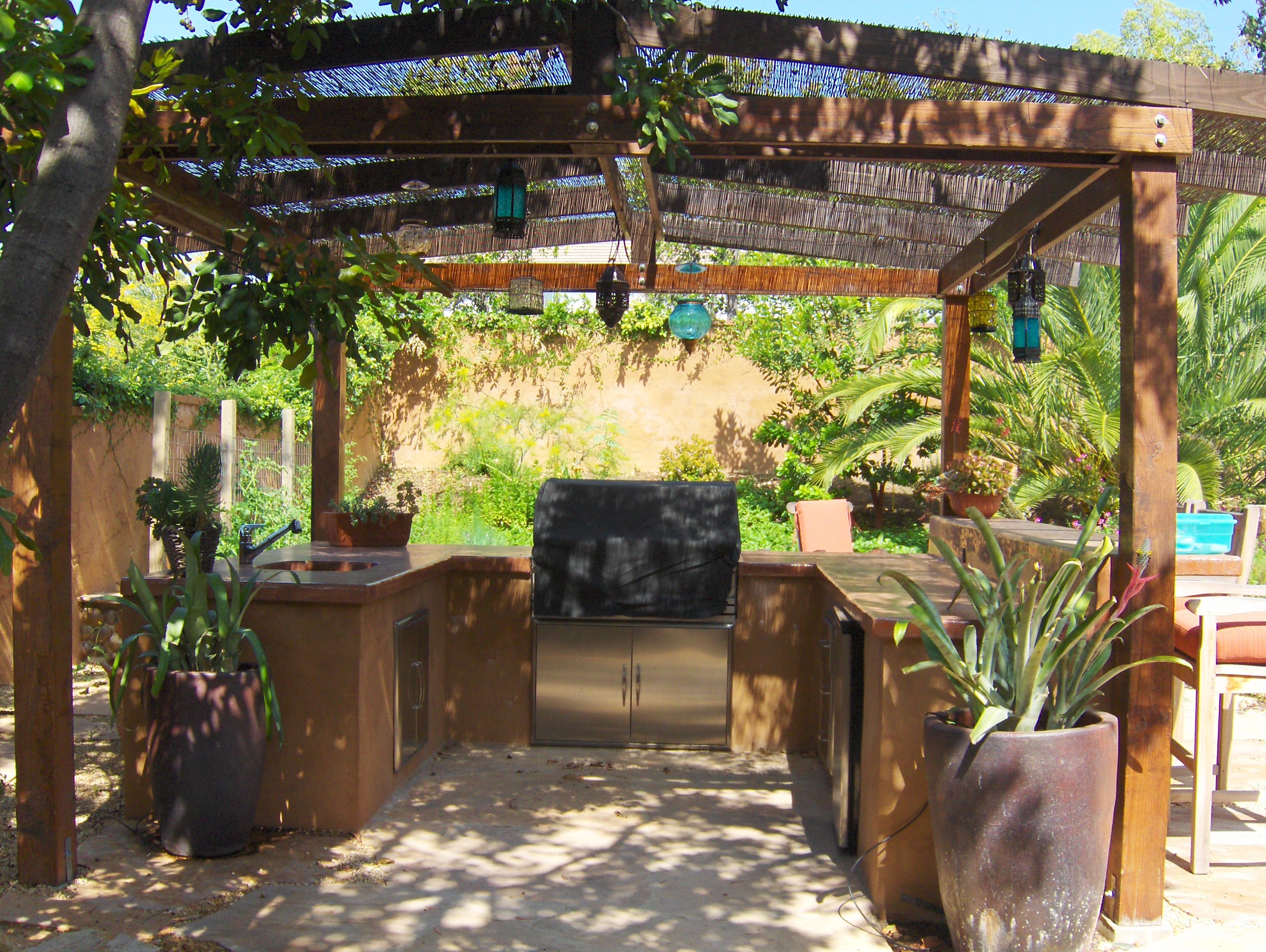 Barbeque under gazebo and hanging plants.